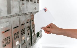A person inserting an envelope into a mail slot.