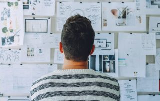 A man studies a wall board full of wireframes